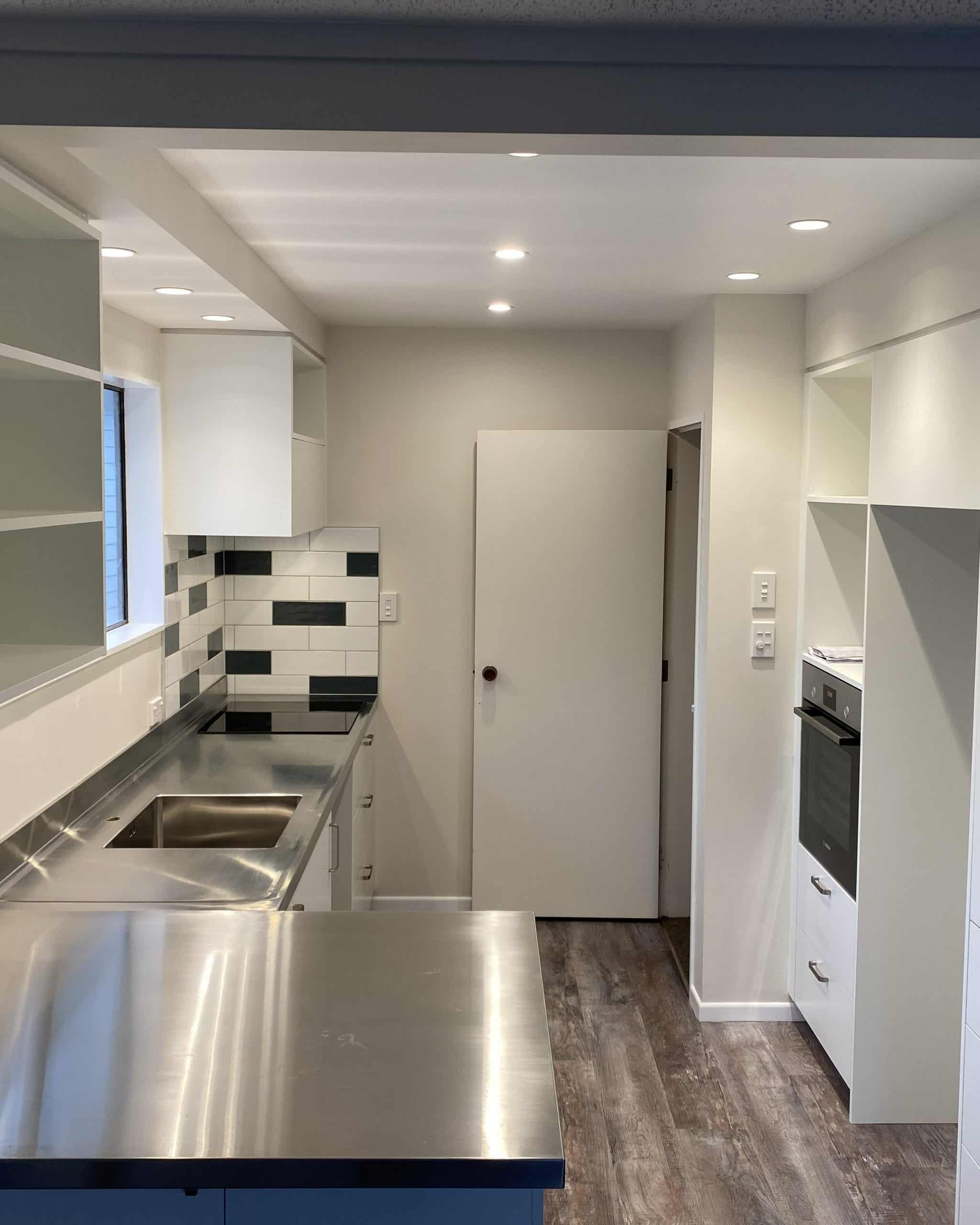 Compact kitchen with white cabinetry, stainless steel worktop and considered storage solutions — Brisbane kitchen design by Zander Edward